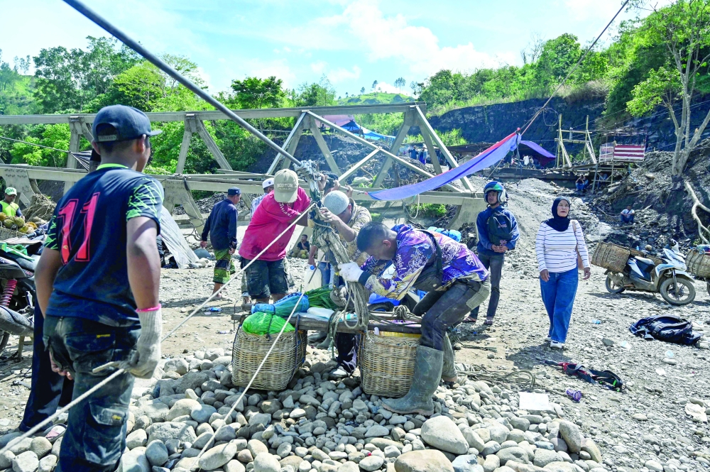 People use a rope to cross a river in the aftermath of flash floods that destroyed adjacent villages in Ketol, Indonesia's Aceh highland province on January 6, 2026. (Photo by CHAIDEER MAHYUDDIN / AFP)
