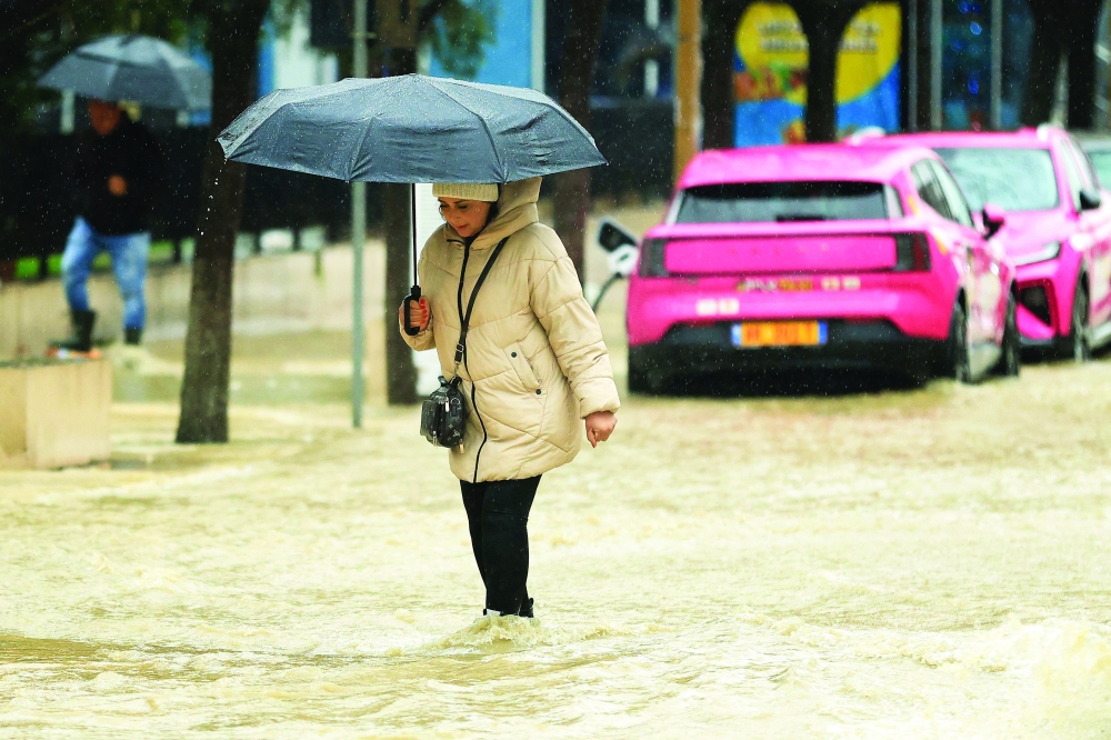 A pedestrian walks along a flooded street in Durres after heavy rainfall caused damage and road blockages across Albania. - AFP