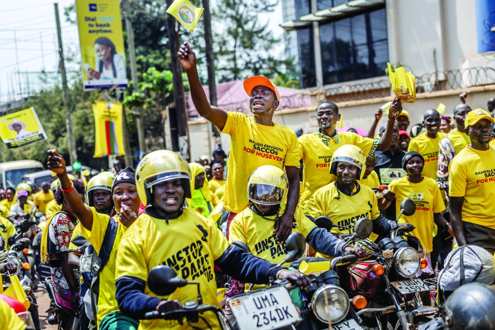 Mototaxi drivers supporting Uganda's incumbent president and National Resistance Movement (NRM) presidential candidate Yoweri Museveni chant slogans and wave flags as they head to the rally grounds ahead of the party closing campaign rally ahead of the 2026 Ugandan general elections, in Kampala on January 13, 2026. (Photo by AFP)