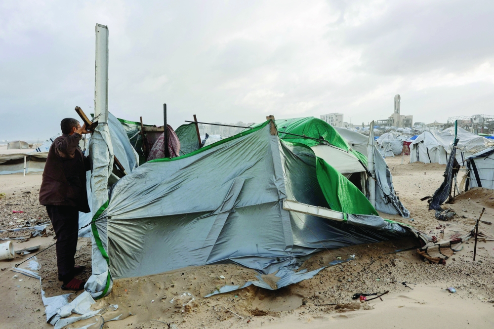 A displaced Palestinian man fixes a tent shelter set up along the shore in Gaza City. — AFP