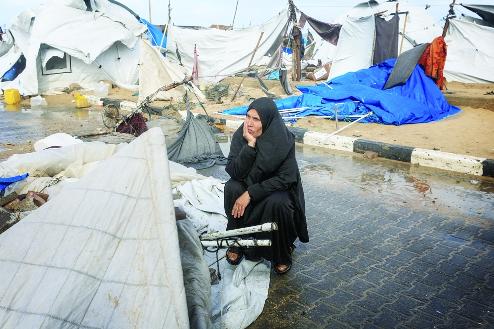 A displaced Palestinian woman sits near damaged tents, in Gaza City. — Reuters