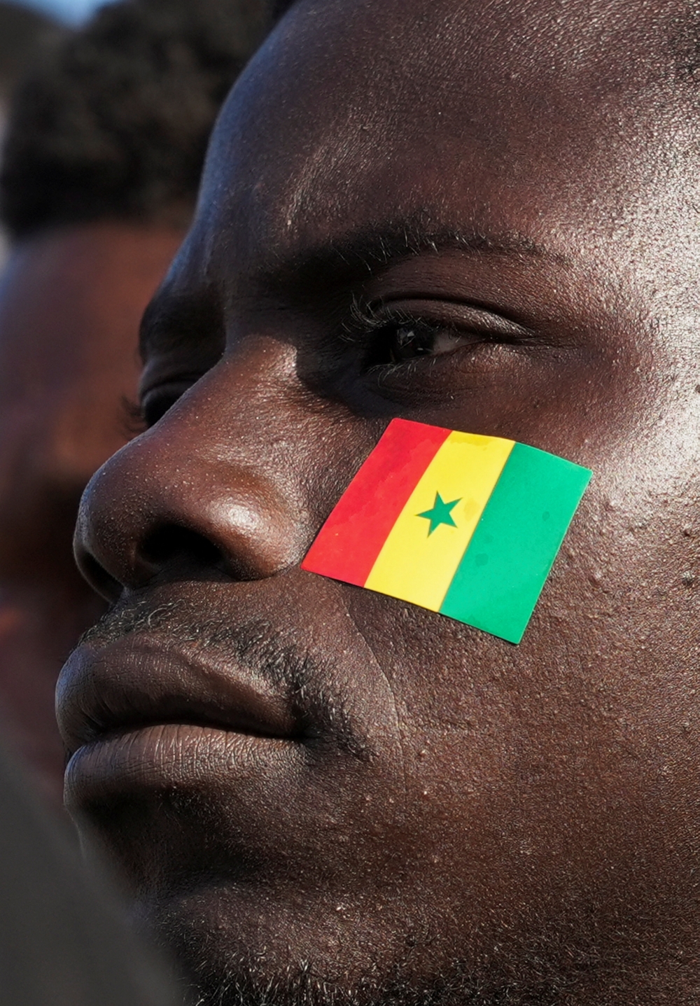 A Senegal team fan looks on while gathering with others  