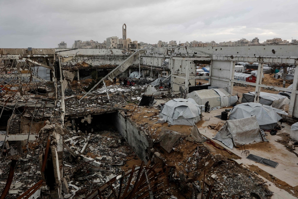 A photograph shows makeshift shelters inside a war-damaged building, parts of which collapsed on a windy winter day in Gaza City on January 13, 2026. 