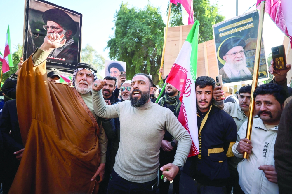 Protesters hold up portraits of Iran's Supreme Leader Ayatollah Ali Khamenei during a demonstration near the Iranian Embassy in Baghdad. — AFP
