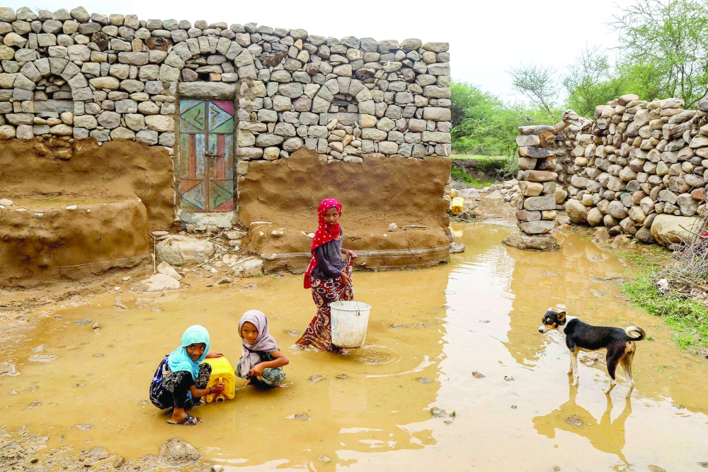 A dog looks on as children fill up a jerrycan from a water puddle left by recent heavy flooding in the Hays region south of Yemen's Hodeidah province on August 28, 2024. The Copernicus Institute releases its report on world temperatures on January 14, 2026. (Photo by Khaled ZIAD / AFP)