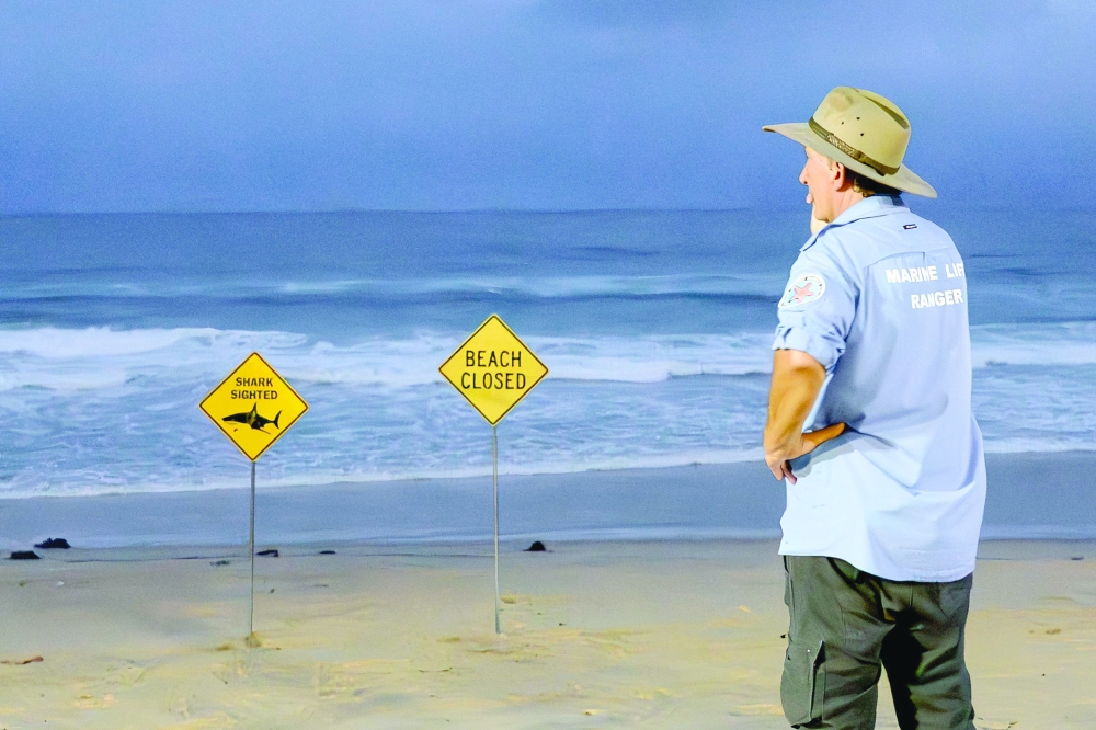 
A marine life ranger stands near the closed signage of the North Steyne Beach in Sydney. — AFP 