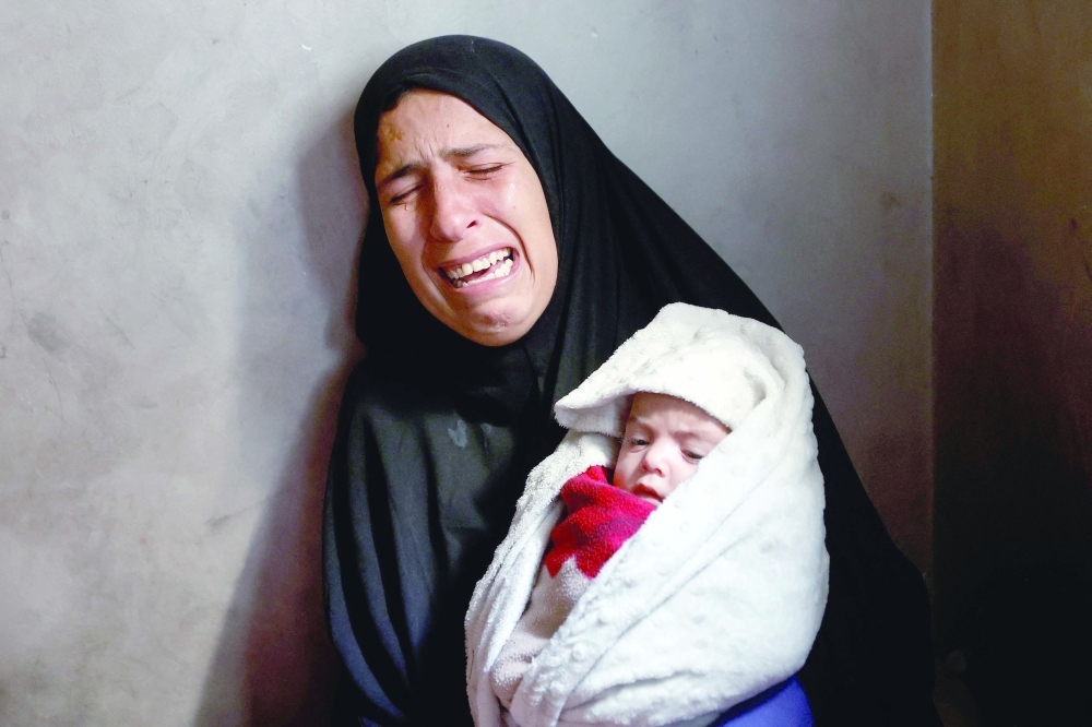 Hiba Abu Jarad, mother of three-month-old Palestinian baby Shatha Abu Jarad, who died of cold weather according to medics, cries while holding Nada, Shatha's twin sister, in Gaza City on Tuesday. - AFP
