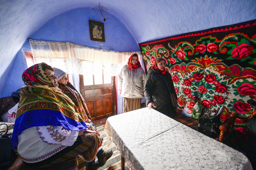 Local women wearing traditional Moldovan clothes gather inside a "basca" museum-house in Rogojeni village.