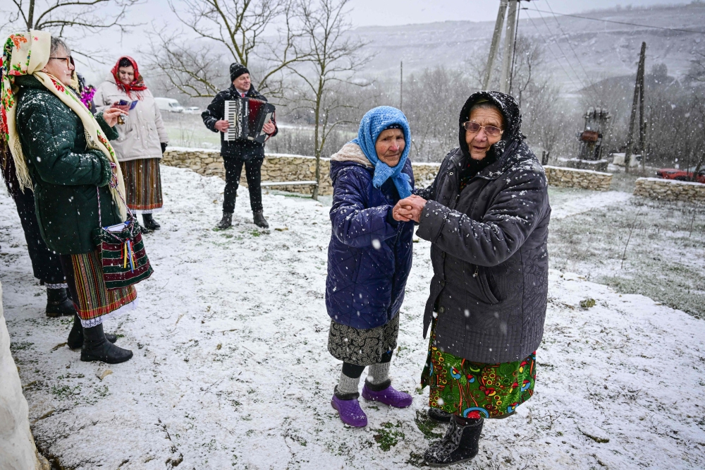 Women wearing traditional Moldovan clothes dance and ing Christmas carols  in Rogojeni village