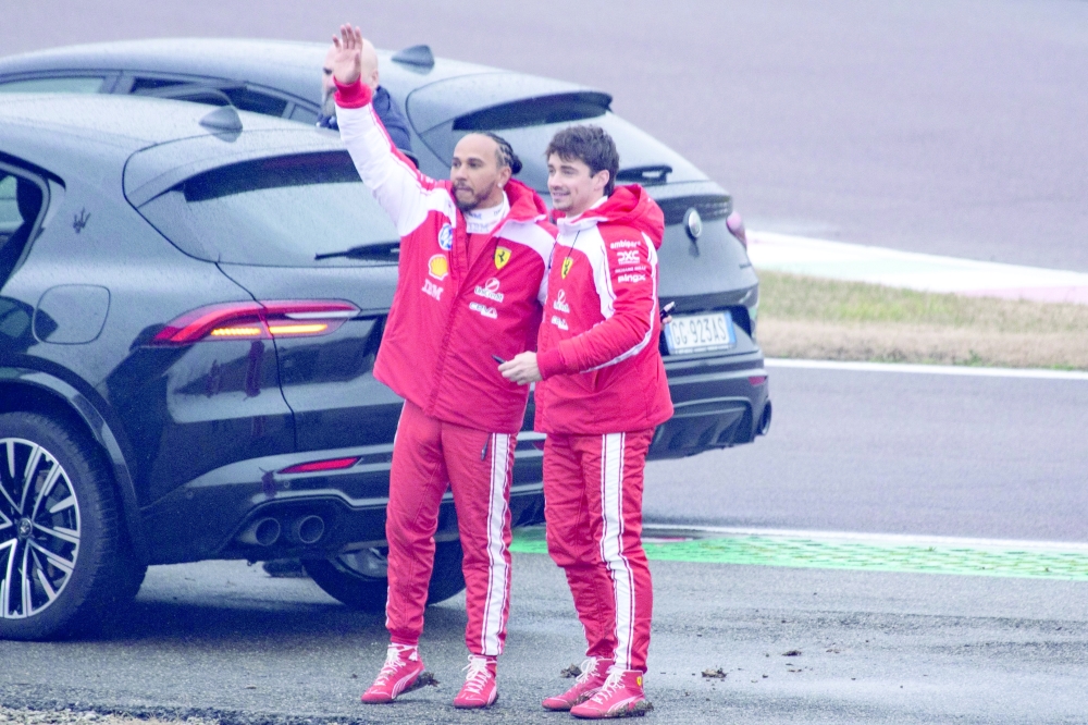 Ferrari's British driver Lewis Hamilton (L) and Ferrari's Monegasque driver Charles Leclerc wave to fans after testing the new Formula 1 Ferrari SF-26 at Fiorano Circuit in Fiorano Modenese on January 23, 2026. (Photo by Federico SCOPPA / AFP)
