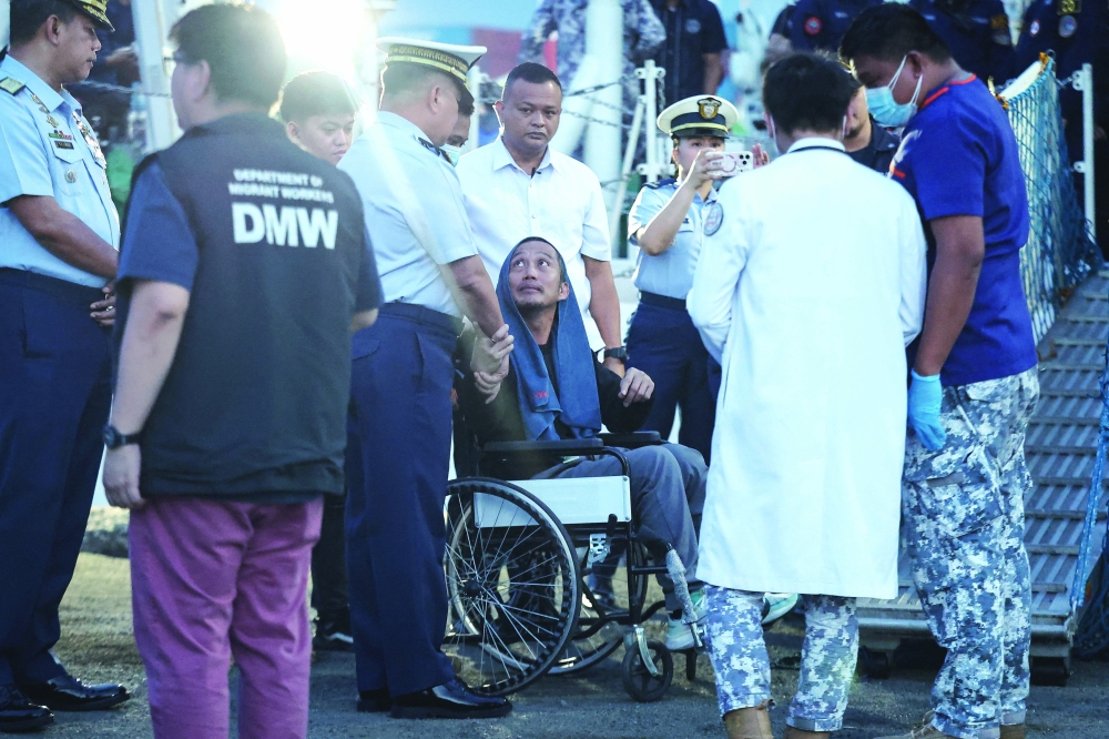 A crew member who survived the sinking disembarks from a Philippine Coast Guard (PCG) vessel at the Port of Manila. — Reuters