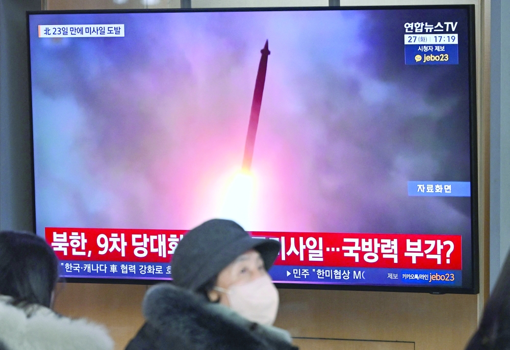People sit in front of a television screen showing file footage of a North Korean missile test, in Seoul. — AFP