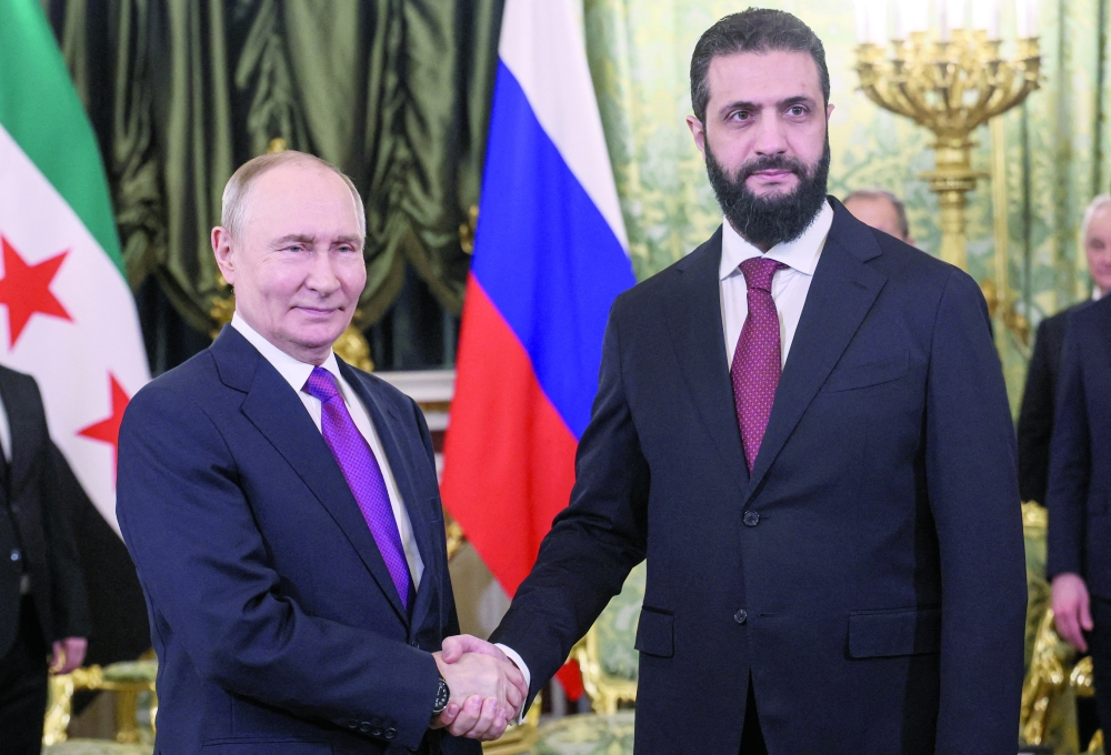 Russian President Vladimir Putin (L) shakes hands with Syrian President Ahmed al Sharaa, at the Kremlin in Moscow.  