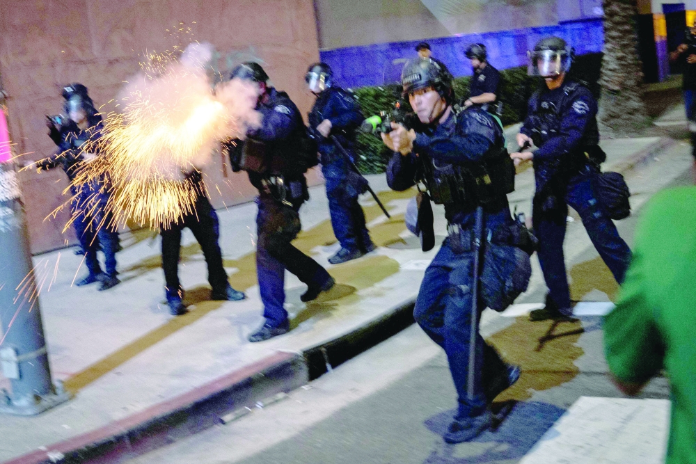 An LAPD officer fires a non-lethal munition while facing protesters during a 'National Shutdown' protest against US Immigration and Customs Enforcement in Los Angeles. — AFP