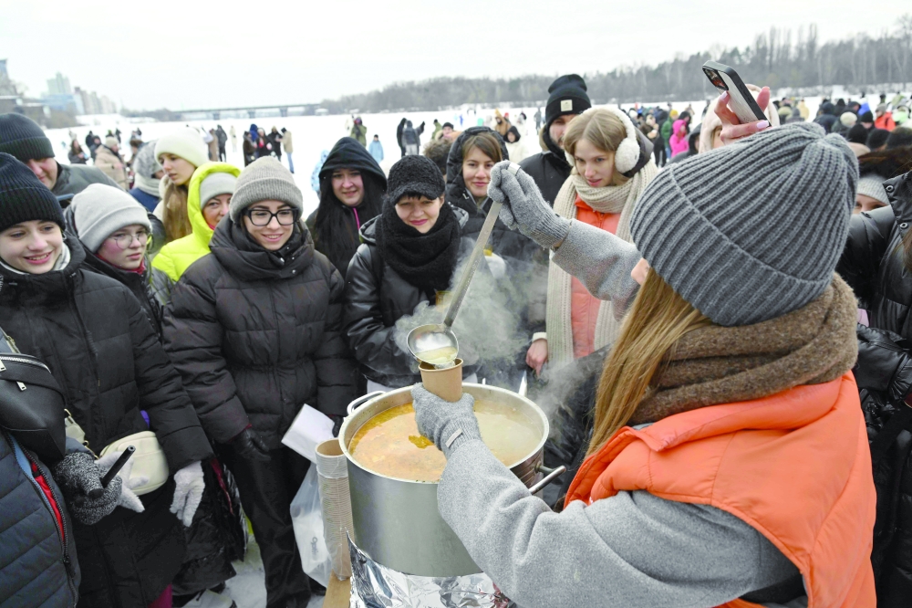 A local restaurant distributes hot soup to attendees of an outdoor party on a side of the frozen Dnipro River in a residential neighbourhood of Kyiv. — AFP
