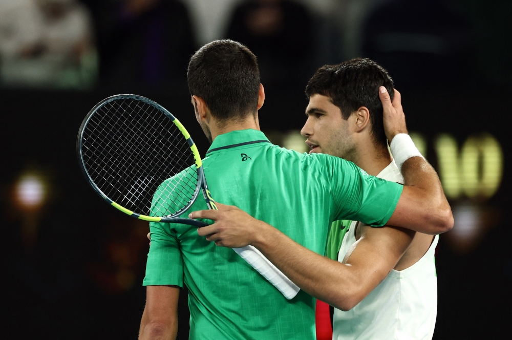 Spain's Carlos Alcaraz celebrates alongside Serbia's Novak Djokovic