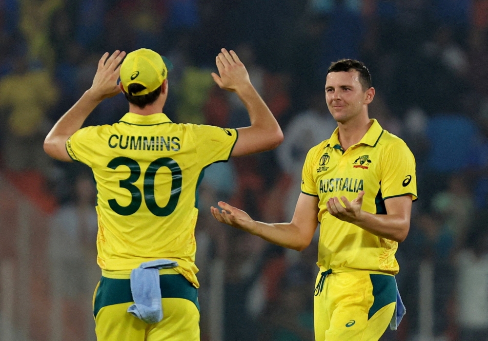 Australia's Josh Hazlewood celebrates with Pat Cummins after taking the wicket of England's Adil Rashid, caught by Josh Inglis 