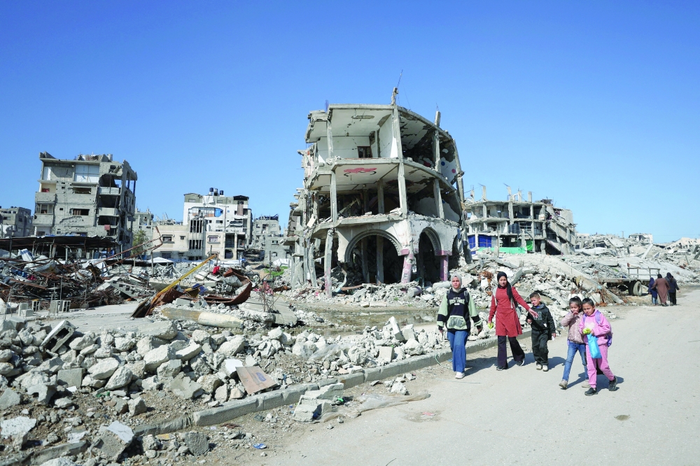 Palestinians walk past the rubble of residential buildings destroyed during Israel’s two-year offensive, in Gaza City
