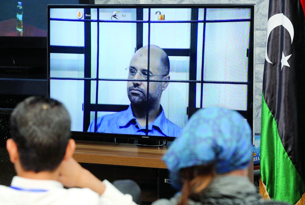 (FILES) Journalists watch as the judges (unseen) question Seif al-Islam (C), the son of slain Libyan dictator Moamer Kadhafi, in a live broadcast from the western Libyan city of Zintan, inside a room in Tripoli on April 27, 2014. Seif al-Islam Kadhafi, the son of Libya's deposed longtime ruler, has died, Libyan media reported on February 3, 2026, without providing details on his death.