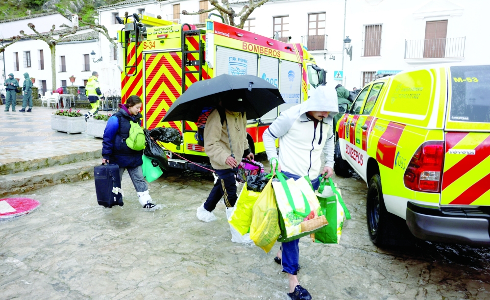 A family carries their belongings as all residents are evicted from their houses due to heavy rains, as storm Leonardo hits parts of Spain in Grazalema. — Reuters