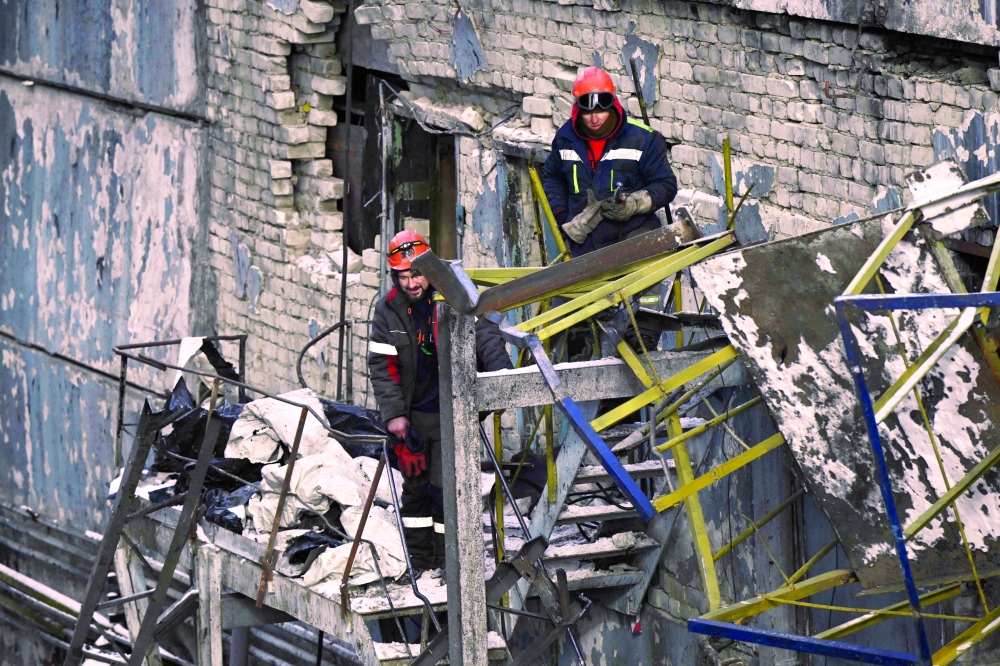 Workers clear debris at a heavily damaged thermal power plant in an undisclosed location in Ukraine. — AFP 
