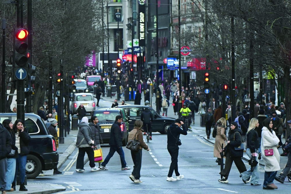 People cross the road as cars are driven on Oxford Street, in central London. _AFP
