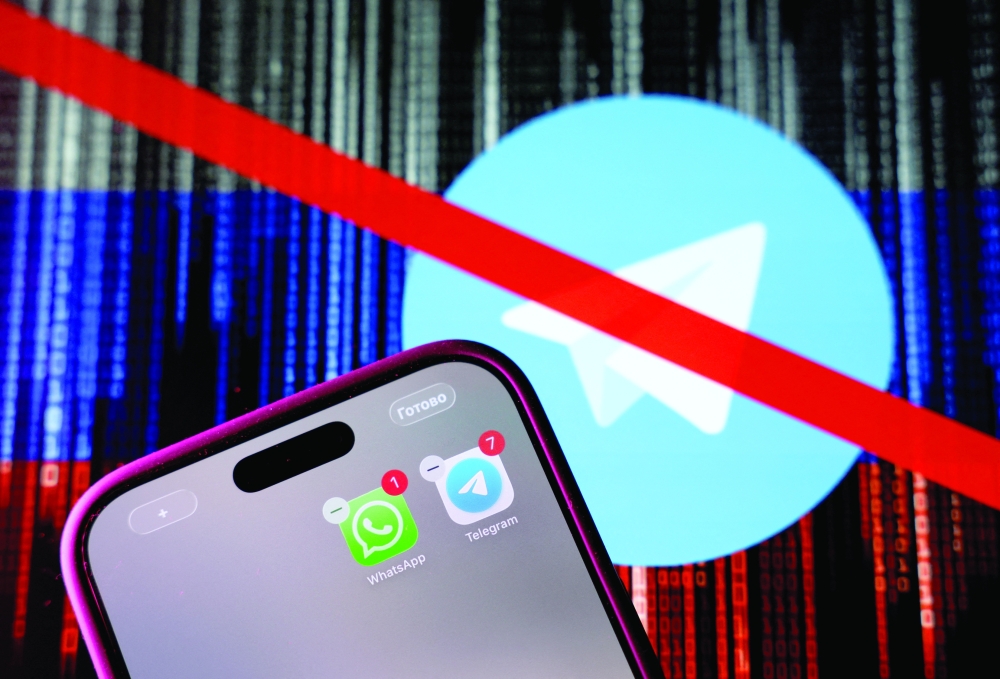 WhatsApp and Telegram messenger app icons displayed on a smartphone in front of a screen showing the crossed logo of Telegram messaging app against the backdrop of numerical codes on the Russian flag. - Reuters