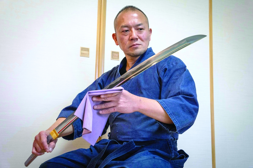 Swordsmith Akihira Kawasaki looking at a katana blade at his workshop in Misato, Saitama prefecture