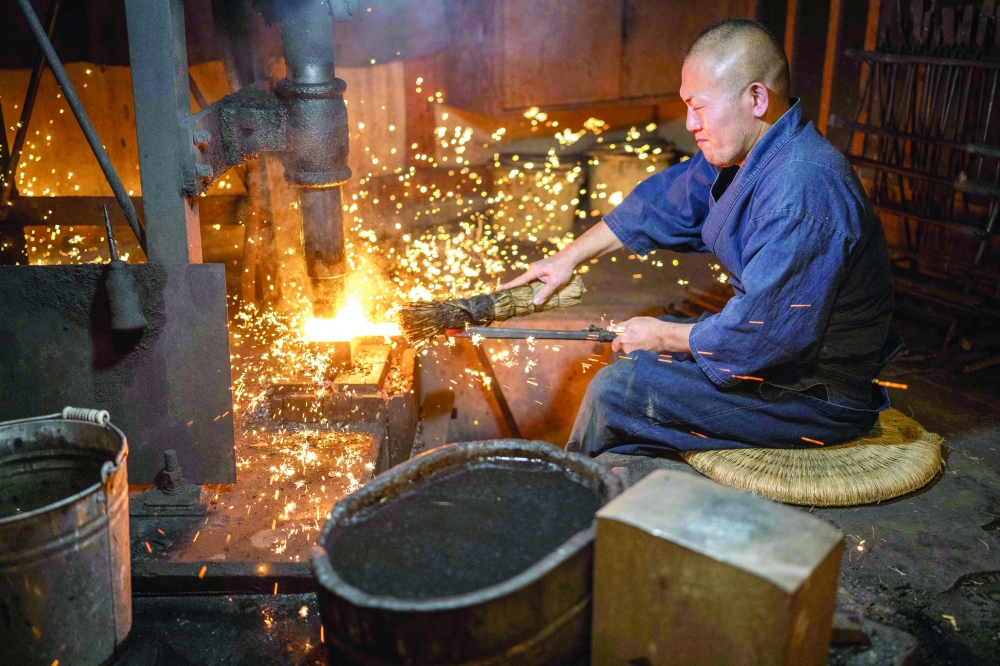 Akihira Kawasaki forges a katana blade with a mechanical hammer at Kawasaki's workshop in Misato