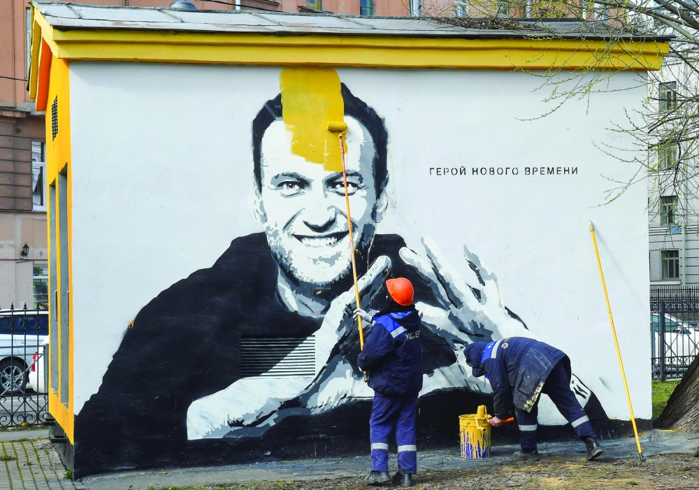 A worker paints over graffiti of jailed Kremlin critic Alexei Navalny in Saint Petersburg. - AFP
