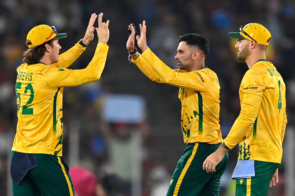 South Africa's Keshav Maharaj (C) celebrates with Dewald Brevis (L) and captain Aiden Markram 