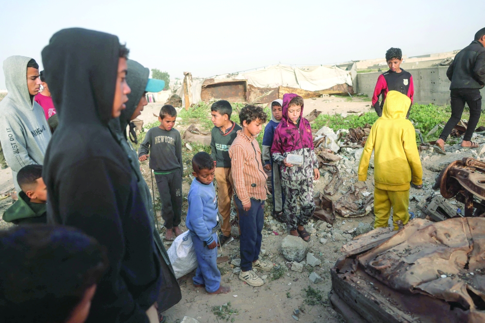Displaced Palestinian gather at the site of an overnight Israeli strike, in the southern Gaza Strip. — AFP