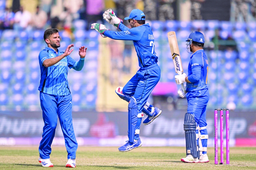 Afghanistan's Azmatullah Omarzai (L) celebrates with wicketkeeper Rahmanullah Gurbaz (C) after taking the wicket of UAE's Harshit Kaushik during the 2026 ICC Men's T20 Cricket World Cup group stage match between Afghanistan and United Arab Emirates at the Arun Jaitley Stadium in New Delhi on February 16, 2026.  (Photo by Arun SANKAR / AFP)
