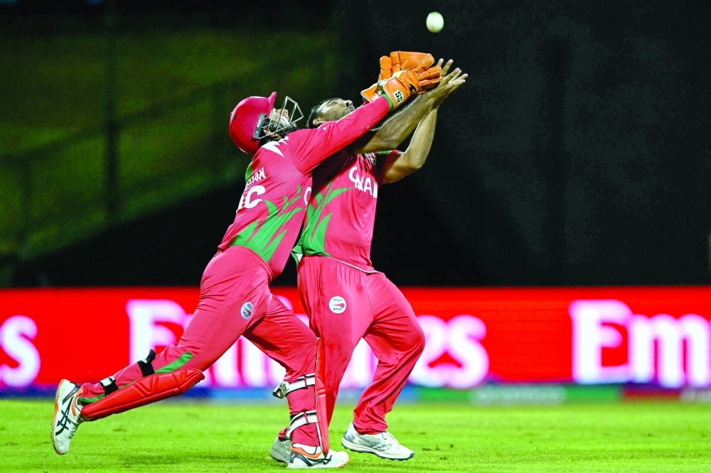 Oman's Shakeel Ahmed (R) and wicketkeeper Vinayak Shukla attempt to take a catch of Australia's Travis Head during the 2026 ICC Men's T20 Cricket World Cup group stage match between Oman and Australia at Pallekele International Cricket Stadium in Kandy on February 20, 2026.  (Photo by Ishara S. KODIKARA / AFP)
