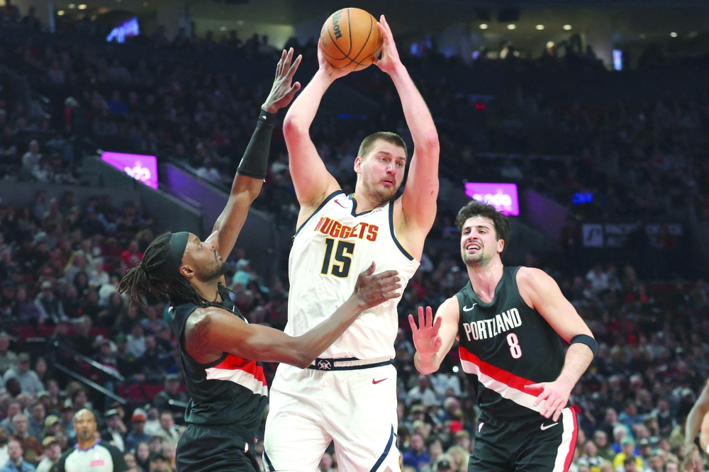 Denver Nuggets center Nikola Jokic (15) grabs a rebound over Portland Trail Blazers guard Jrue Holiday (5) and forward Deni Avdija (8) during. — Imagn Images