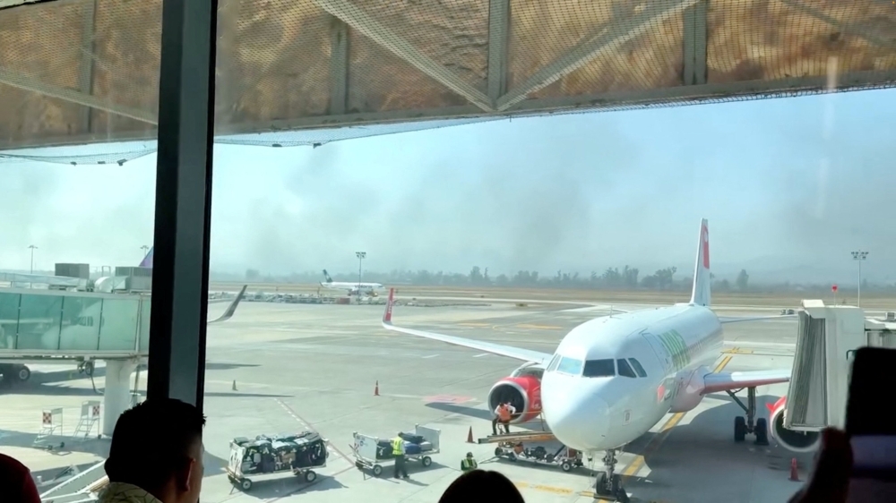 People watch from the Guadalajara International Airport as smoke billows amid a wave of violence, in Tlajomulco de Zuniga