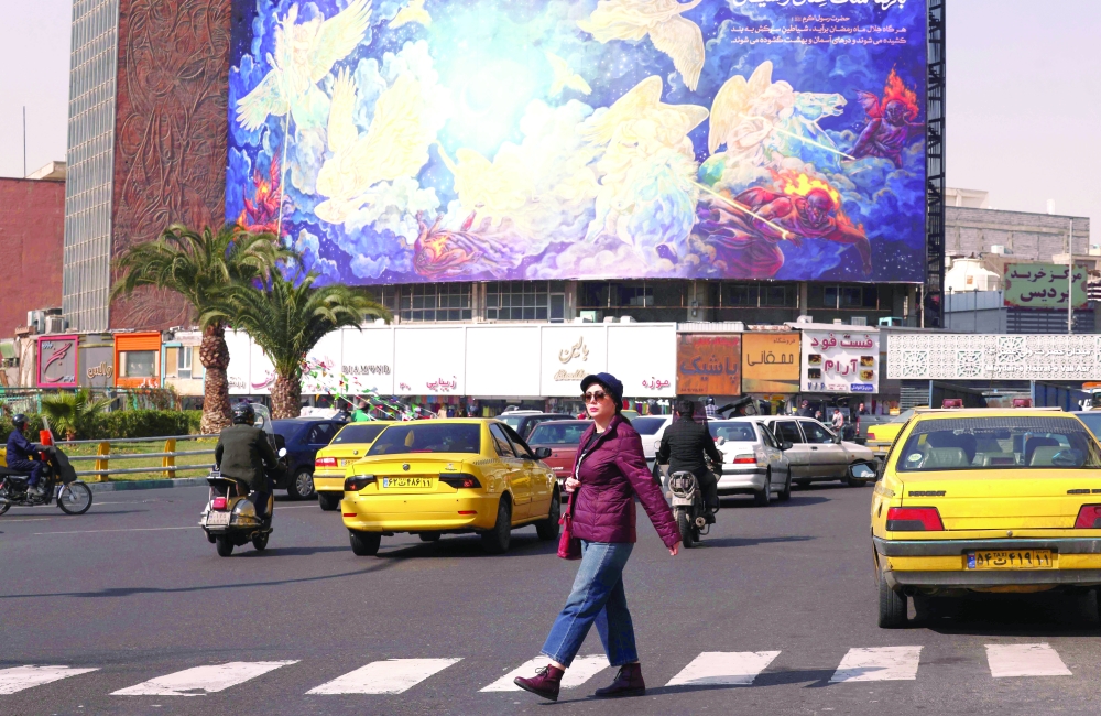 An Iranian woman walks past a huge billboard, in Tehran. — AFP