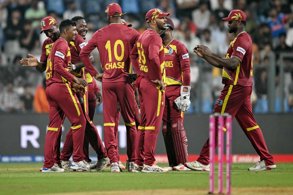 West Indies' Gudakesh Motie (2L) celebrates with teammates after taking the wicket of Zimbabwe's Dion Myers during the 2026 ICC Men's T20 Cricket World Cup Super Eights match between West Indies and Zimbabwe at the Wankhede Stadium in Mumbai on February 23, 2026.  (Photo by Indranil MUKHERJEE / AFP)
