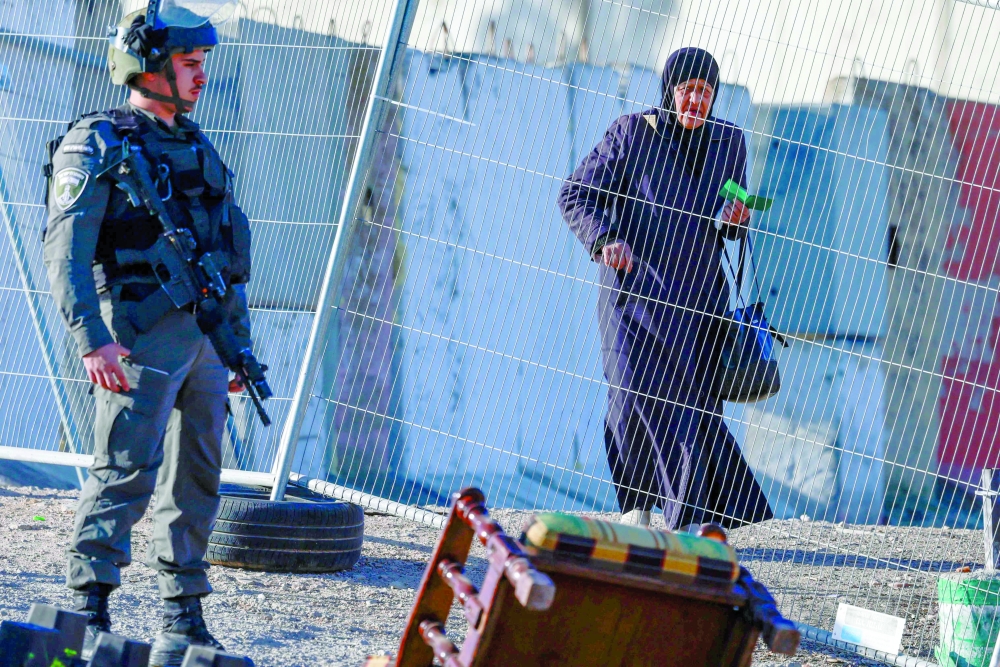 An Israeli soldier keeps watch as a Palestinian woman arrives at the Qalandia checkpoint, in Ramallah. — AFP