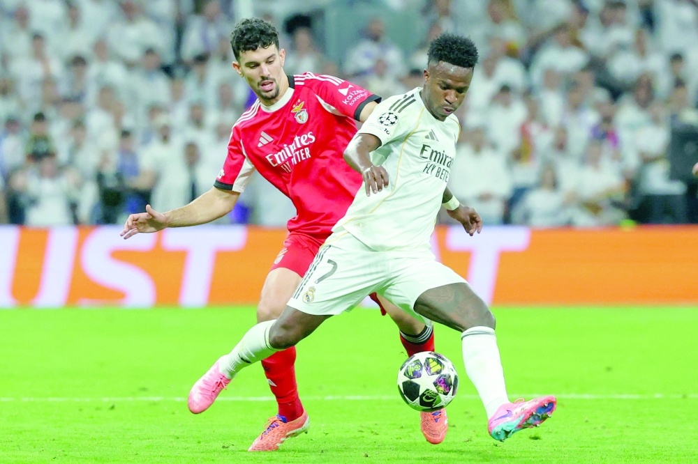 Real Madrid's Brazilian forward #07 Vinicius Junior (R) is challenged by SL Benfica's Portuguese defender #44 Tomas Araujo during the UEFA Champions League knockout round play-off second leg football match between Real Madrid CF and SL Benfica at Santiago Bernabeu Stadium in Madrid on February 25, 2026.  (Photo by Pierre-Philippe MARCOU / AFP)
