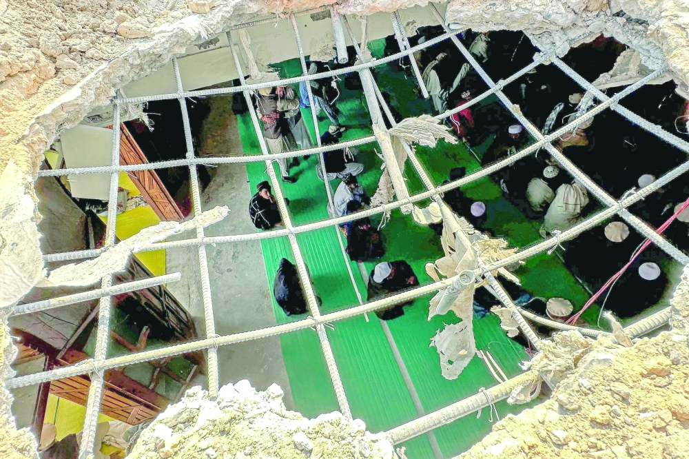 Residents gather to offer Friday prayers inside a mosque damaged during overnight cross-border fighting between Pakistan and Afghanistan in Bajaur, Khyber Pakhtunkhwa province. — AFP