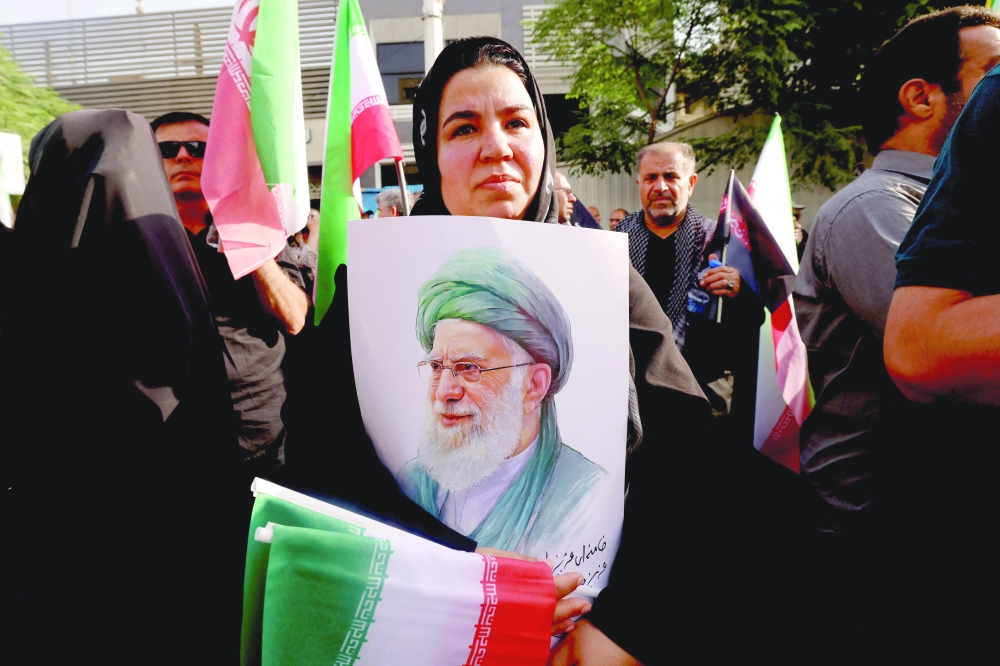 A mourner holds up a poster showing the image of Iran's Supreme Leader Ali Khamenei, in Tehran. — AFP