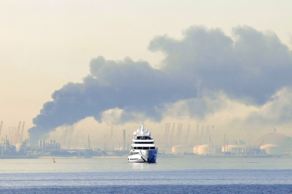 A yacht sails past a plume of smoke rising from the port of Jebel Ali following a reported Iranian strike in Dubai. — AFP