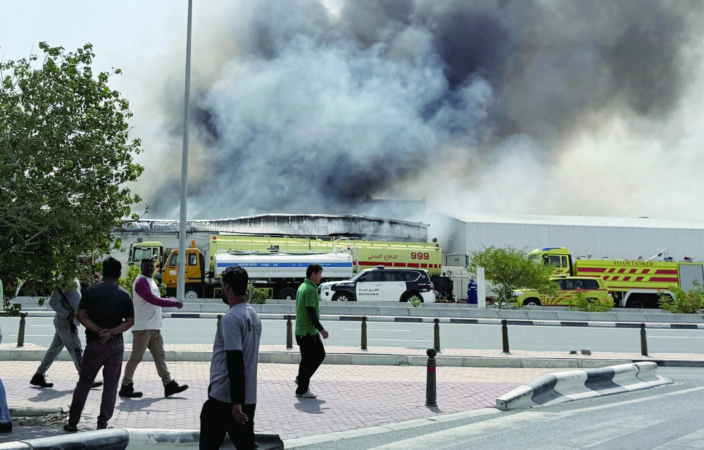 People gather as smoke rises at the Industrial Area after reported Iranian missile attacks, in Doha. — Reuters