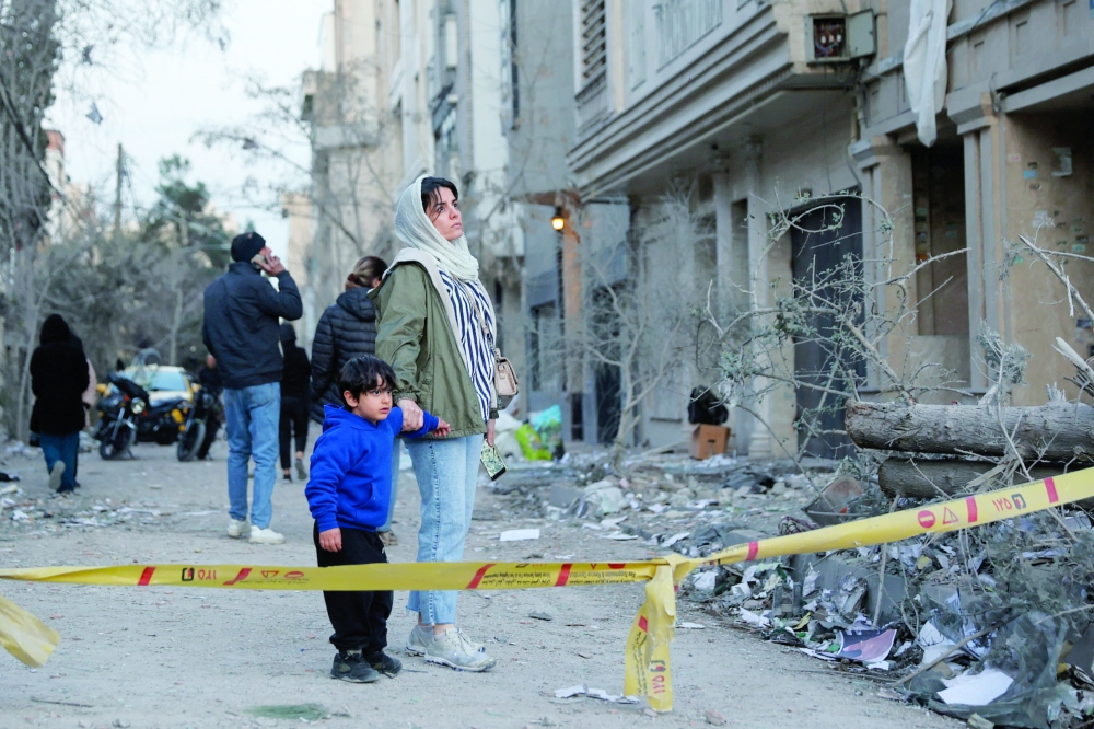 
A woman with her child looks at the aftermath of an Israeli and US strike in Tehran. — Reuters 