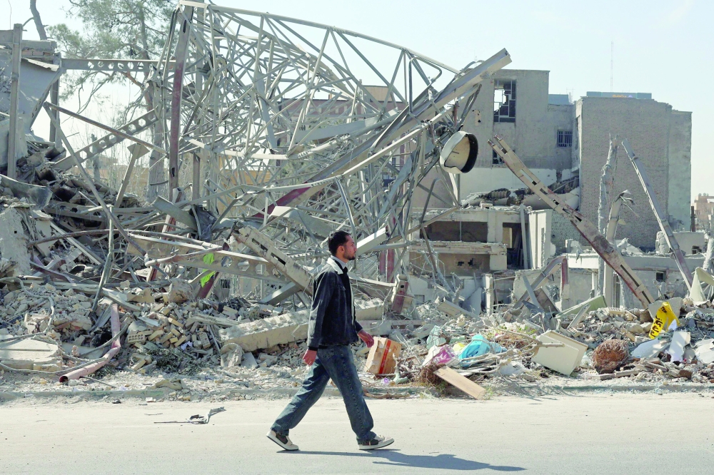 A man walks past destroyed buildings following air strikes in central Tehran on Wednesday. - AFP