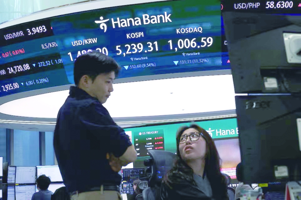 Currency dealers talk in front of an electronic board displaying the Korea Composite Stock Price Index (KOSPI), the exchange rate between the U.S. Dollar and South Korean Won and the Korea Securities Dealers Automated Quotations (KOSDAQ) at the dealing room of a bank in Seoul, South Korea. REUTERS