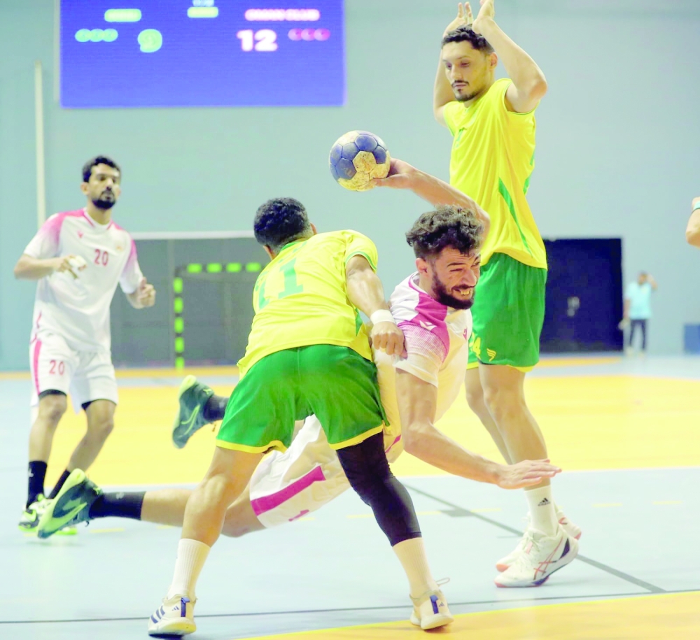 Oman Club player past Seeb defense during an intense handball encounter.  