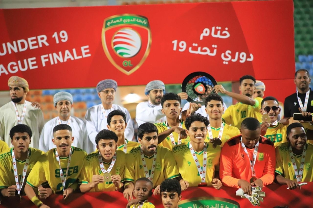 Seeb players celebrate with the trophy on the podium