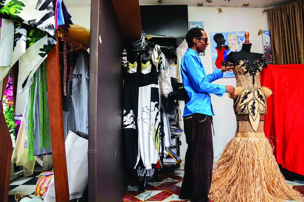 Gabonese fashion designer Chouchou Lazare makes final adjustments on a dress inside his tailoring workshop in Libreville on February 9, 2026.  Chouchou Lazare a self-taught award winning designer, learned everything by creating dresses for the two women who matter most in his life: his mother and his grandmother. Lazare uses raffia, a natural fibre material extracted from palm leaves as a signature for his designs. (Photo by Nao Mukadi / AFP)
